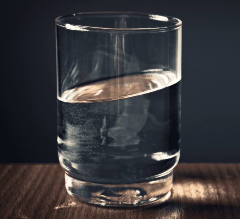Glass kept on a table, dark background.