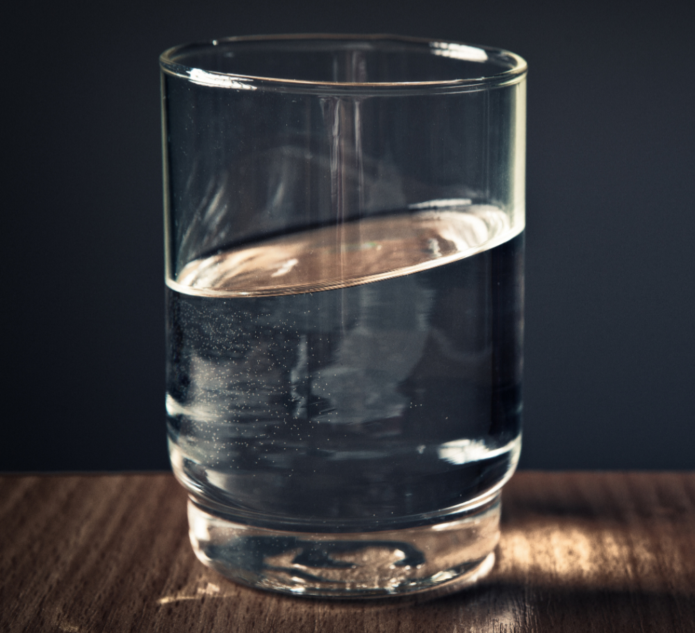 Glass kept on a table, dark background.